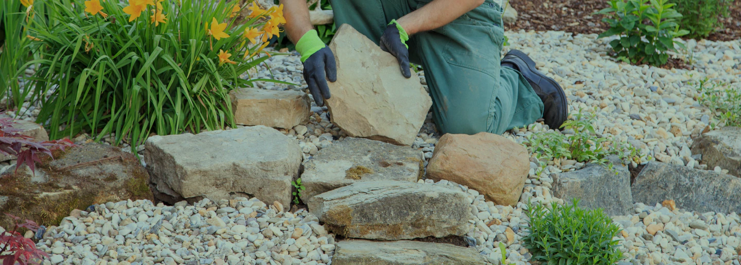 man creating dry creek beds with big stones